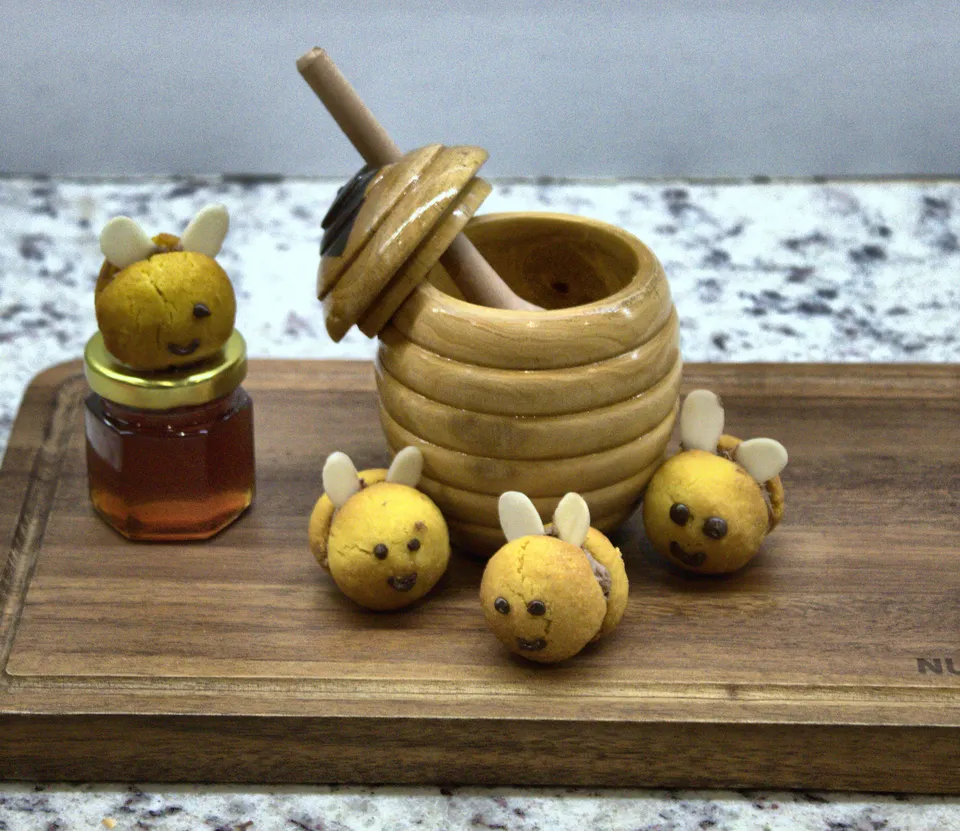 Piezas en forma de abeja junto a un tarro de miel de madera